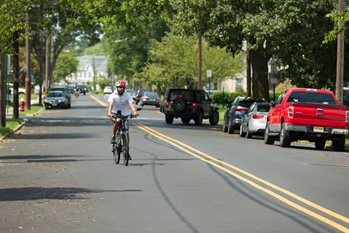 A man rides a bike down a suburban street